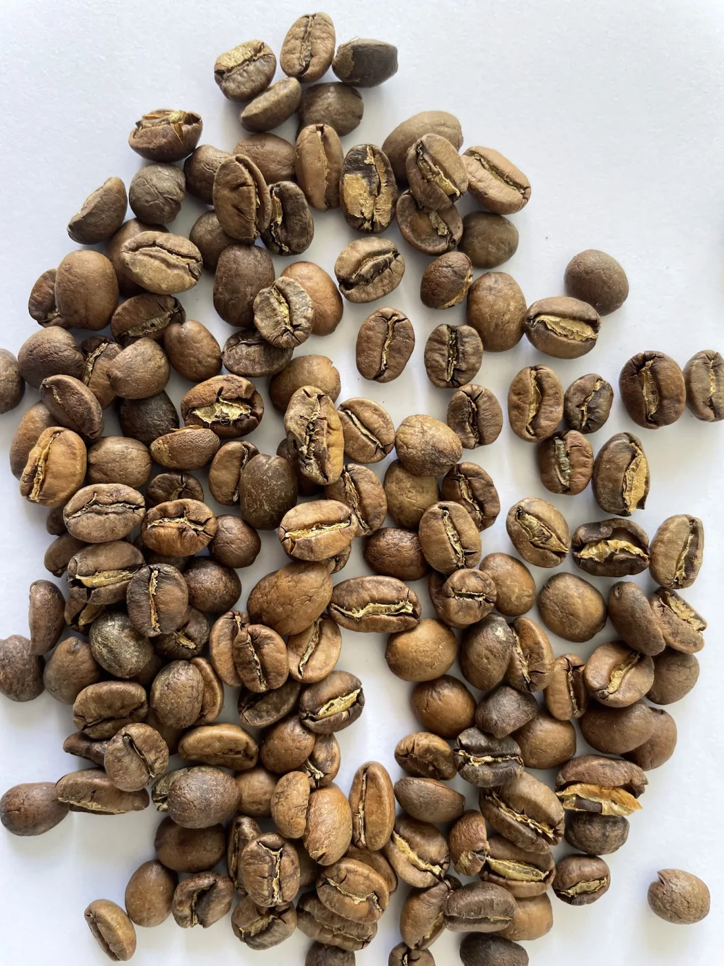 Light-roasted coffee beans scattered on a white surface